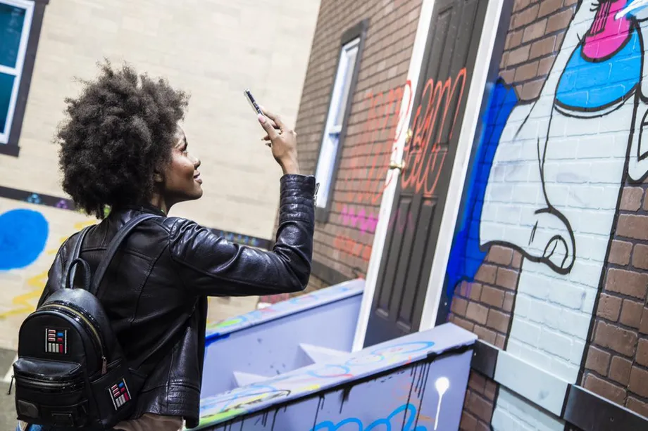 Immagine di una ragazza che riprende un graffito con lo smartphone