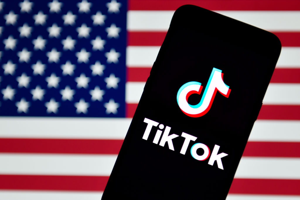 CHINA - 2020/09/14: In this photo illustration a TikTok logo is seen displayed on a smartphone with the USA flag in the background.